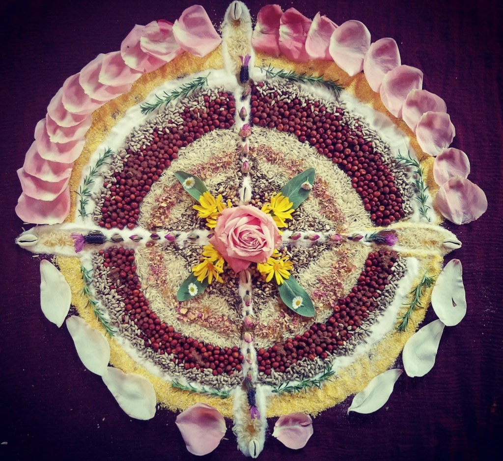 Offering mandala of seeds, grains, rose petals and flowers arranged in a circle with four directions